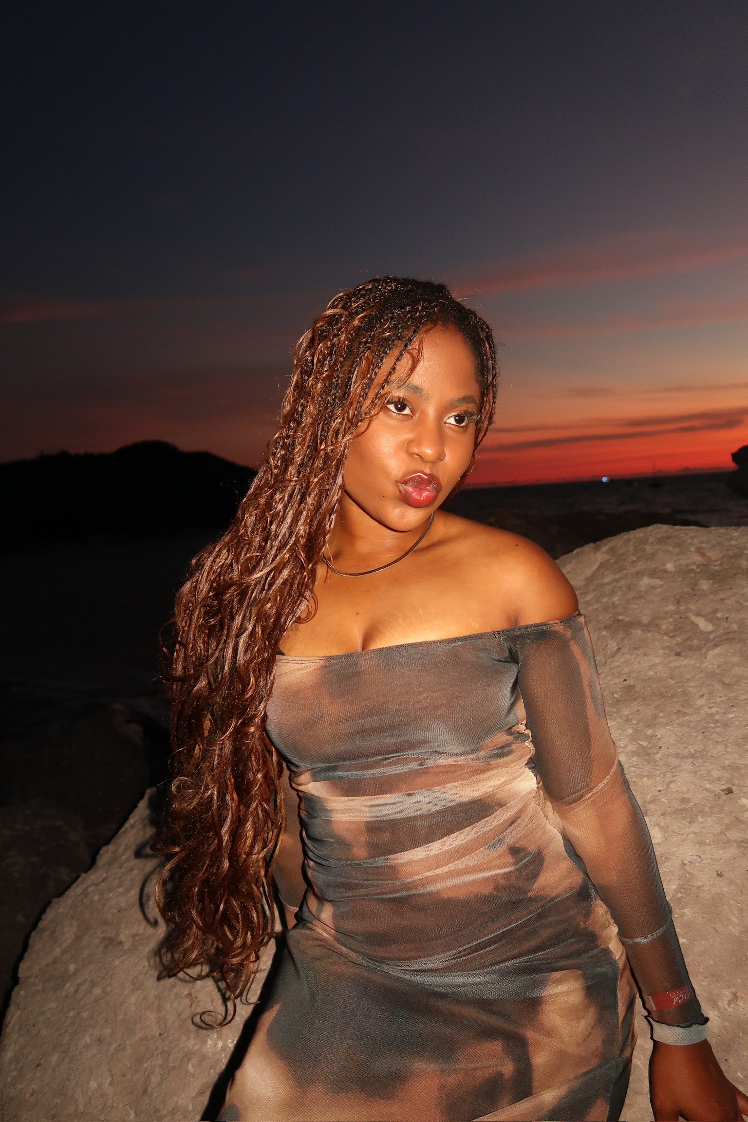 Dara Belle seated by the sea at sunset